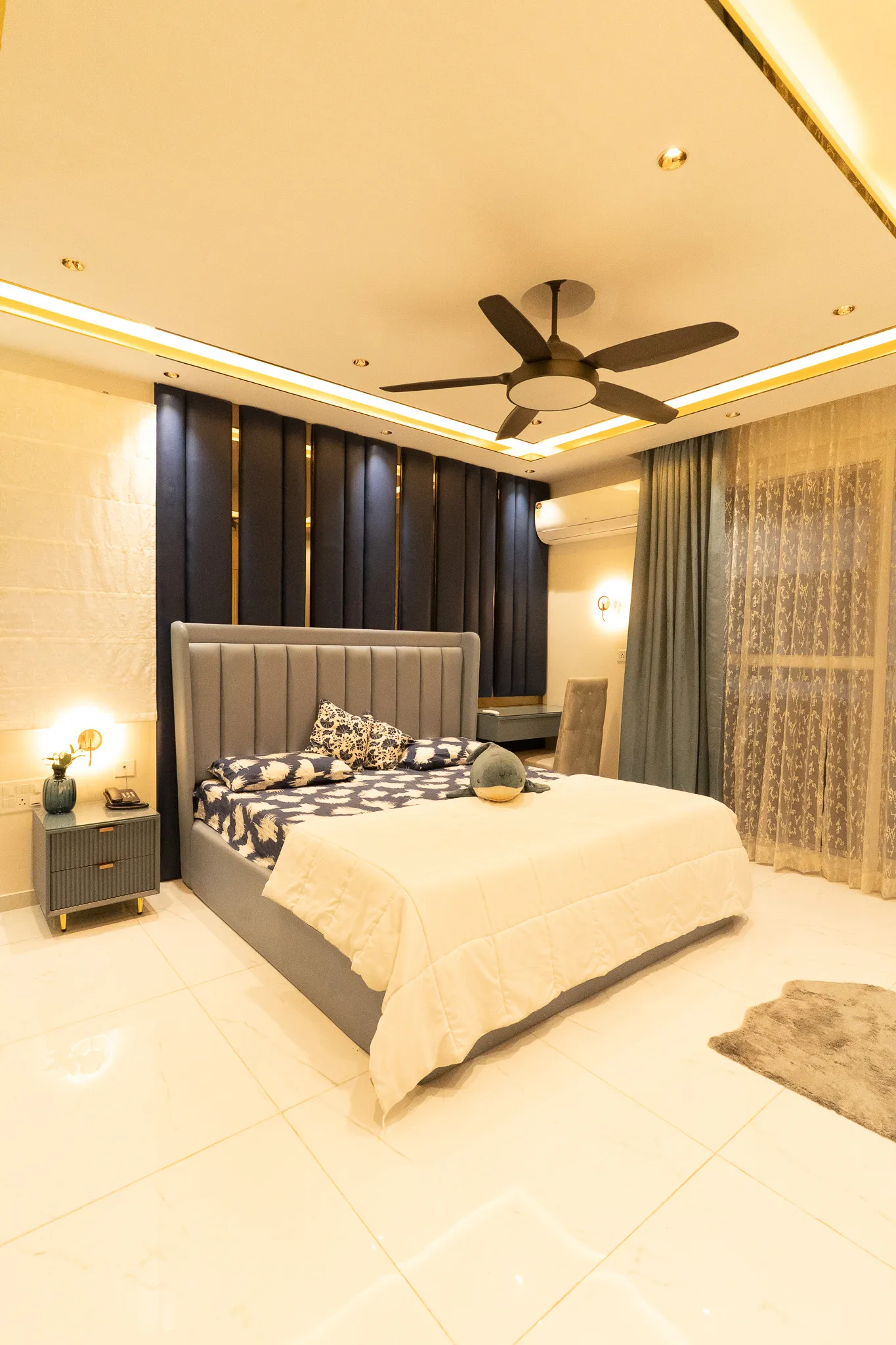 Bedroom with grey upholstered bed and dark fluted wall — Divyarjuna